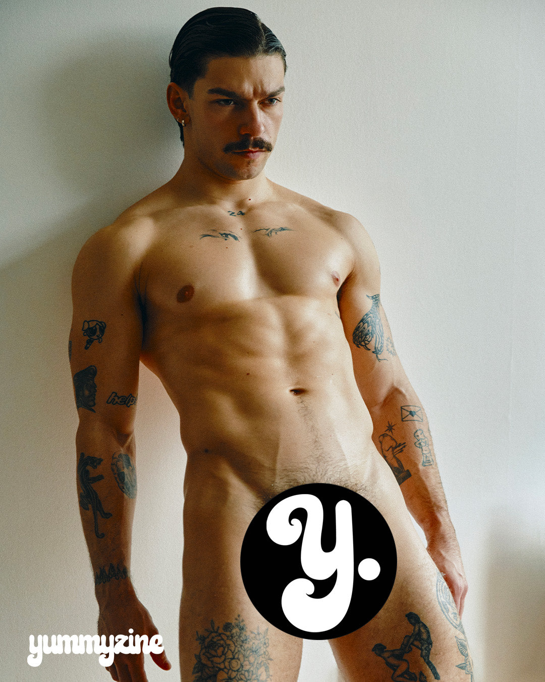 A man with tattoos poses against a neutral background.